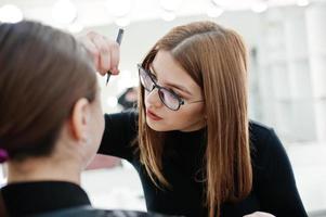 Make up artist work in her beauty visage studio salon. Woman applying by professional make up master. Beauty club concept. photo