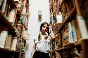 Girl with pigtails in white blouse at old library. photo