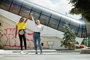 niña caucásica blanca y afroamericano negro juntos contra la pared de graffiti. unidad mundial, amor racial, comprensión en la tolerancia y cooperación en la diversidad de razas. foto