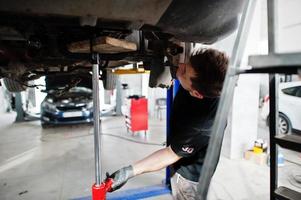 Car repair and maintenance theme. Mechanic in uniform working in auto service. photo