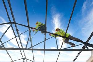 los trabajadores de la construcción usan arneses de seguridad y arneses de seguridad que trabajan en techos industriales de metal. foto