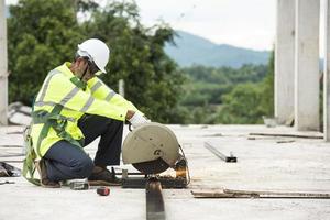 un trabajador de la construcción con una amoladora de acero está cortando una tubería de acero brillantemente iluminada. foto