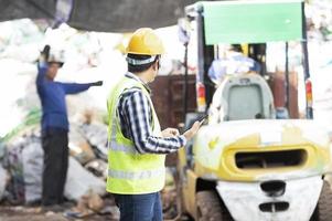 Close-up of a worker with a recycling bin moving a forklift in a steel mill waste collection plant. photo