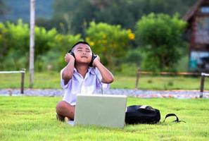 Schoolchildren enjoy listening to music with headphones on the lawn, redido headphones. photo
