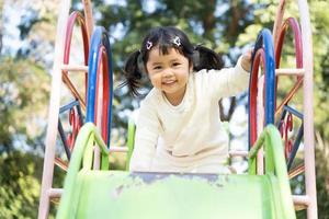 Cute asian girl play on school or kindergarten yard or playground. Healthy summer activity for children. Little asian girl climbing outdoors at playground. Child playing on outdoor playground.