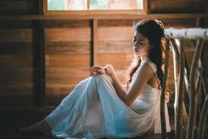Sad asian woman wearing white dress suffering depression insomnia awake and sit alone on the bed in vintage bedroom. sexual harassment and violence against women. photo