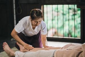 Massage and spa relaxing treatment of office syndrome using hot stone traditional thai massage style. Asain female masseuse doing foot massage treat stress for woman. photo