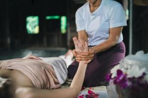 Massage and spa relaxing treatment of office syndrome using hot stone traditional thai massage style. Asain female masseuse doing hand massage treat stress for woman. photo