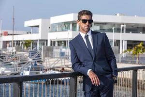 Male executive leaning on railing in port photo