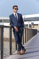 Businessman resting on footbridge near water photo