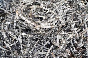 Steel scrap materials recycling. Aluminum chip waste after machining metal parts on a cnc lathe. Closeup twisted spiral steel shavings. Small roughness sharpness, photo