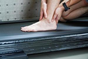 Asian man hurts his ankle while running on a treadmill,concept of not wearing shoes while running on a treadmill photo