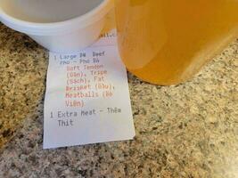 Vietnamese pho soup broth with receipt saying extra meat photo