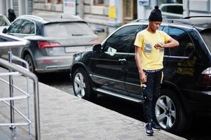 African man wear on black hat posed outdoor against business car. photo