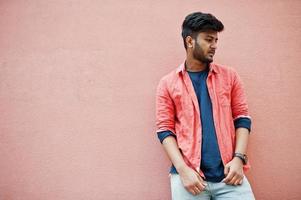 Portrait of young stylish indian man model isolated on pink wall background. photo