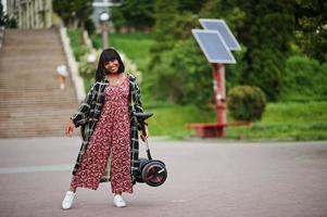 Beautiful african american woman hold on hands segway or hoverboard. Black girl with dual wheel self balancing electrical scooter. photo