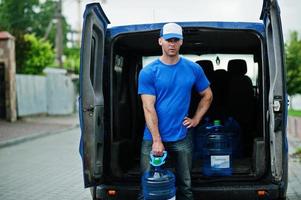 repartidor en camioneta de carga delantera entregando botellas de agua. foto