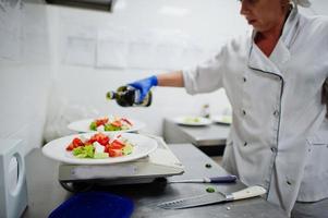 Female chef preparing salad in italian restaurant kitchen. photo