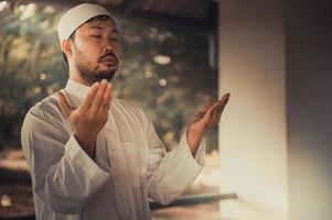 oración del hombre islámico asiático, oración musulmana joven, concepto del festival de ramadán foto