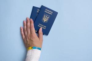 Passports of a citizen of Ukraine and female hand on a blue background, close-up. Inscription in Ukrainian Ukraine Passport photo