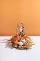 Autumn creative composition. Dried leaves wreath, pumpkins and candle on white orange background. Autumn fall and thanksgiving day concept. Still life photo