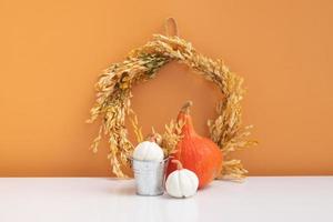 Autumn composition. Dried leaves wreath, pumpkins, on white orange background. Autumn fall ans thanksgiving day concept. Still life photo