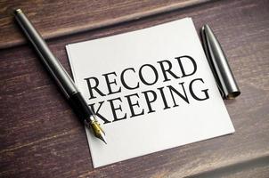 RECORD KEEPING text concept write on notebook on a wooden background photo