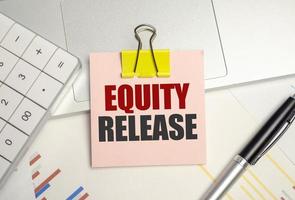 Equity Release symbol. pink paper sheet and pen, calculator and charts photo