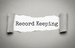 RECORD KEEPING text on white torn paper photo