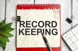 RECORD KEEPING words on white notepad and pen photo