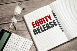 Equity Release words on brown diary and glasses, calculator and pen on wooden desk photo