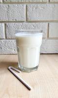 A glass of kefir on the table with a paper tube photo