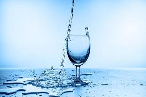 water splashing from glass isolated on blue background photo