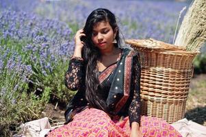 hermosa niña india usa vestido tradicional saree india en campo de lavanda púrpura. foto