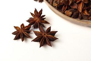 star anise illicium verum in a wooden spoon isolated on white background