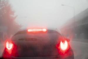 abstracto y borroso de la parte trasera del coche blanco rojo luz de freno. la lluvia dispersa que empaña todo alrededor no está clara. tormenta en la carretera con diferentes puentes a los lados. foto