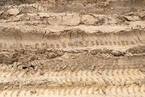 Beside view of liquid mud off road and there are marks of tires. photo