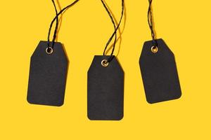 Group of three Blank black tags isolated on yellow background. Template Mock up photo