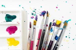 Art Paint brushes, palette and colorful splatter on white canvas paper photo