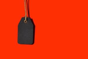 Blank black tag isolated on red background with copy space. Template Mock up photo