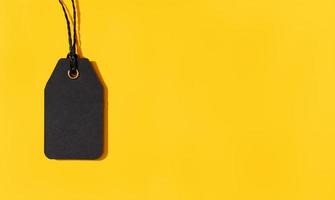 Blank black tag isolated on yellow background with copy space. Template Mock up photo