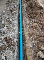 The new PVC pipe is laying in the trench near the asphalt road. photo