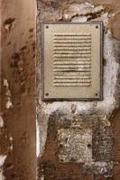 Metal grid cover set in a grungy old brown wall photo