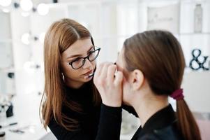 Make up artist work in her beauty visage studio salon. Woman applying by professional make up master. Beauty club concept. photo