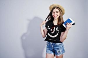 chica turista con pasaporte, vestida con camisa jajaja, pantalones cortos y sombrero aislado en blanco. foto