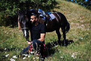 Arab tall beard man wear in black with arabian horse. photo