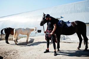 Arab tall beard man wear in black helmet with arabian horse. photo