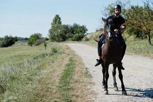 Arab tall beard man wear in black helmet, ride arabian horse. photo