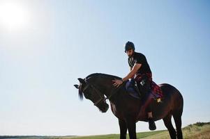 Arab tall beard man wear in black helmet, ride arabian horse. photo