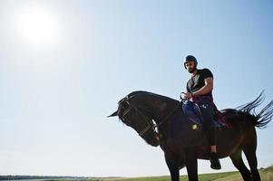 Arab tall beard man wear in black helmet, ride arabian horse. photo